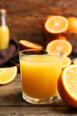Glass of tasty orange juice on wooden background