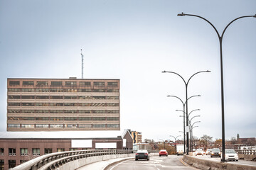 Vehicles climb the elevated Rosemont Boulevard past twin curved lampposts by a blocky office warehouse on an afternoon that highlights the city's busy industrial roadway in Montreal, Quebec, Canada.