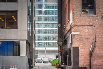 Typical Dead End street lines up between steel glass offices and a brick warehouse, wisps of steam...