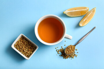 Cup of hot buckwheat tea with lemon slices on blue background