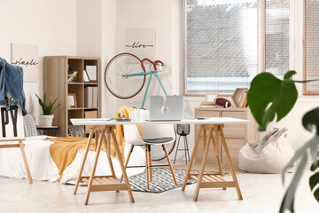 Interior of teenager's room with bed, workplace and bicycle