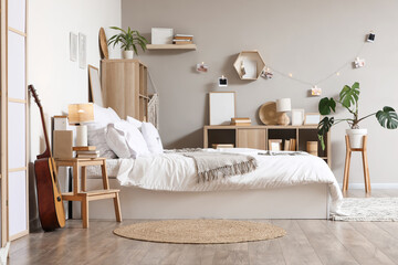 Interior of light teenager's room with bed, guitar and bookshelves