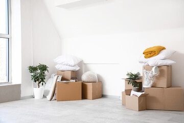 Cardboard boxes with things near light wall in room on moving day