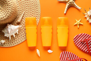 Composition with beach accessories, starfish, seashells and bottles of sunscreen cream on orange...