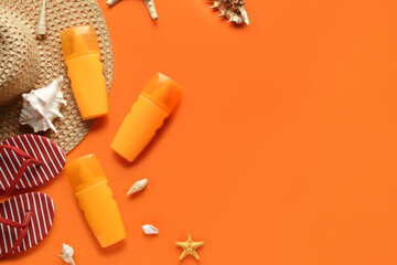 Composition with beach accessories, starfish, seashells and bottles of sunscreen cream on orange background