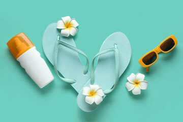 Composition with sunglasses, flip-flops, plumeria flowers and bottle of sunscreen cream on...