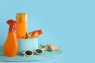 Composition with bottles of sunscreen cream and beach accessories on blue background