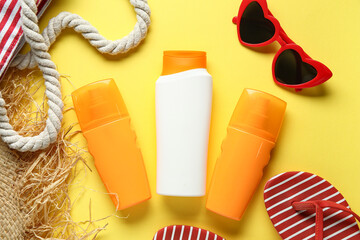 Composition with bag, hat, bottles of sunscreen cream and sunglasses on yellow background
