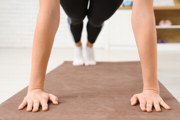 Sporty young woman training on fitness mat at gym, closeup