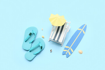 Composition with seashells, decorative deckchair, flip-flops, surfboard and umbrella on blue...