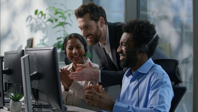 Happy callcenter boss Caucasian businessman looking computer applauding cheering call center business multiethnic workers African man Indian woman headset work success helpline internet trading office