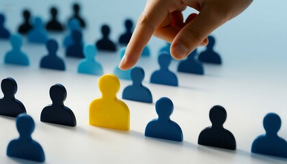 A finger points to a single yellow figure among many blue and black figures symbolizing selection individuality and standing out from the crowd