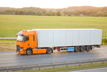 Sustainable Orange Freightliner Gliding Through Rural Transport Corridor