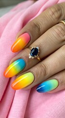 Obraz premium Woman s hand with colorful ombre nails and a sapphire engagement ring