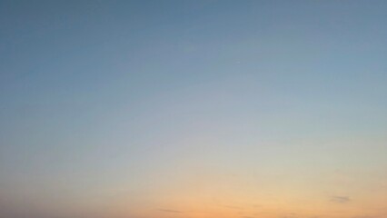 A serene sunrise sky with a subtle gradient from soft blue to warm orange at the horizon, featuring...