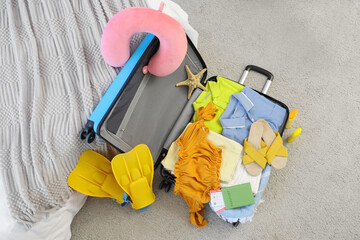 Packed suitcase with clothes and beach accessories on carpet in room, closeup