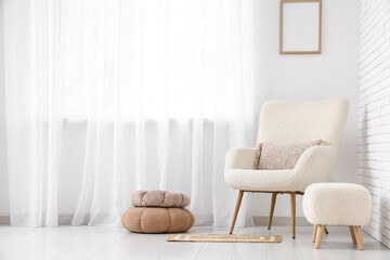 Interior of light living room with white armchair and poufs near big window, closeup