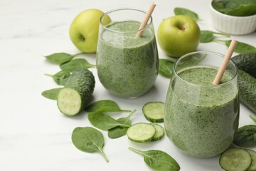 Tasty spinach smoothie and ingredients on white table, closeup