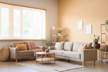 Obraz premium Interior of living room with shelving unit, table and grey sofas near beige wall