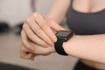 Woman checking fitness tracker during training indoors, closeup