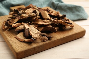 Pieces of dried mushrooms on light wooden table, closeup