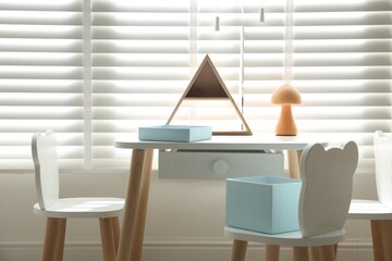 Small table, chairs and decor in stylish playroom. Interior design