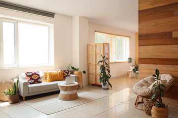 Interior of light room with sofa, table and modern laptop near window