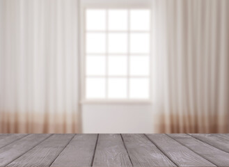 Empty wooden table against window with curtains in room