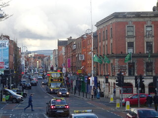 Red brick buildings and iconic Dublin buses on a lively main street with green flags