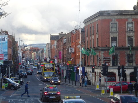 Red brick buildings and iconic Dublin buses on a lively main street with green flags