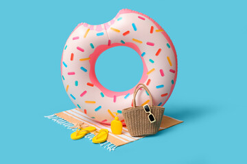 Inflatable ring in shape of donut, bottle of sunscreen cream and beach accessories on blue...