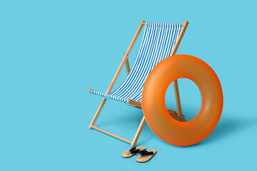 Inflatable ring, deckchair and flip-flops on blue background, closeup