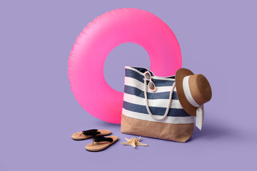 Inflatable ring and beach accessories on lilac background, closeup