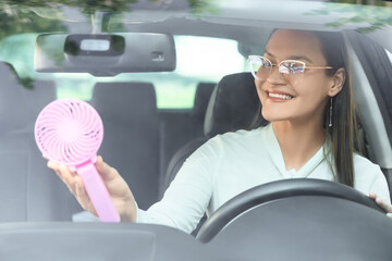Young woman with mini electric fan in car