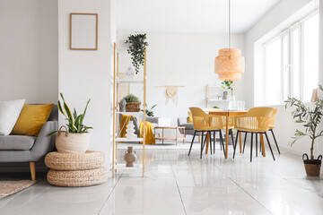Poufs, shelving unit, table, chairs and houseplants in interior of room