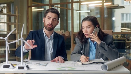 Korean businesswoman engineer Caucasian businessman speaking renewable ecology project wind turbine...