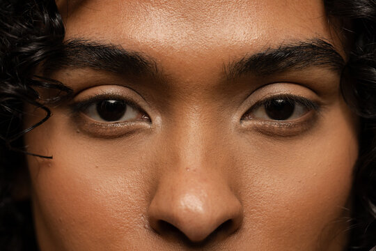 Non-binary individual staring straight ahead in studio with dark backdrop focusing on expression