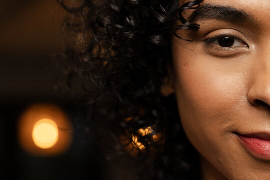 Non-binary African American Asian person showing curly hair in studio with bokeh light, copy space