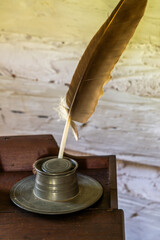 A feather quill and pewter ink well