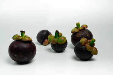 A vibrant collection of ripe raw mangosteen fruits arranged on a white background.

