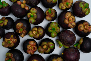 A vibrant collection of ripe raw mangosteen fruits arranged on a white background.
