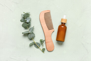 Hair comb, eucalyptus twig and bottle of cosmetic product on green background © Pixel-Shot