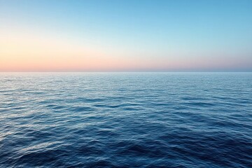 Fototapeta premium Calm vast ocean under a clear blue sky with gentle waves at sunset or sunrise creating a peaceful and serene atmosphere