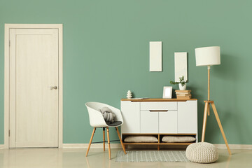Chest of drawers, armchair, pouf and floor lamp in interior of living room