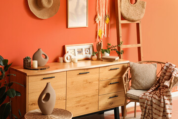 Chest of drawers, stepladder, armchair and table near orange wall in living room, closeup