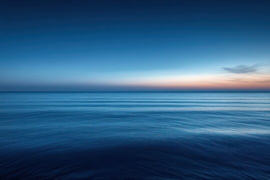 Calm ocean at dusk with clear blue sky and gentle waves reflecting soft fading sunlight, evoking peaceful and serene atmosphere - Powered by Adobe
