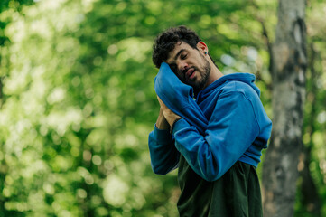 Tired athlete wiping sweat with towel in forest after training