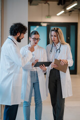Fototapeta premium Medical team discussing patient data using tablet and clipboard in hospital corridor