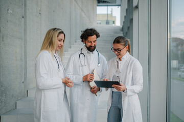Doctors using tablet and discussing diagnosis in hospital hallway