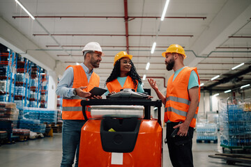 Warehouse workers discussing logistics using digital tablet and forklift